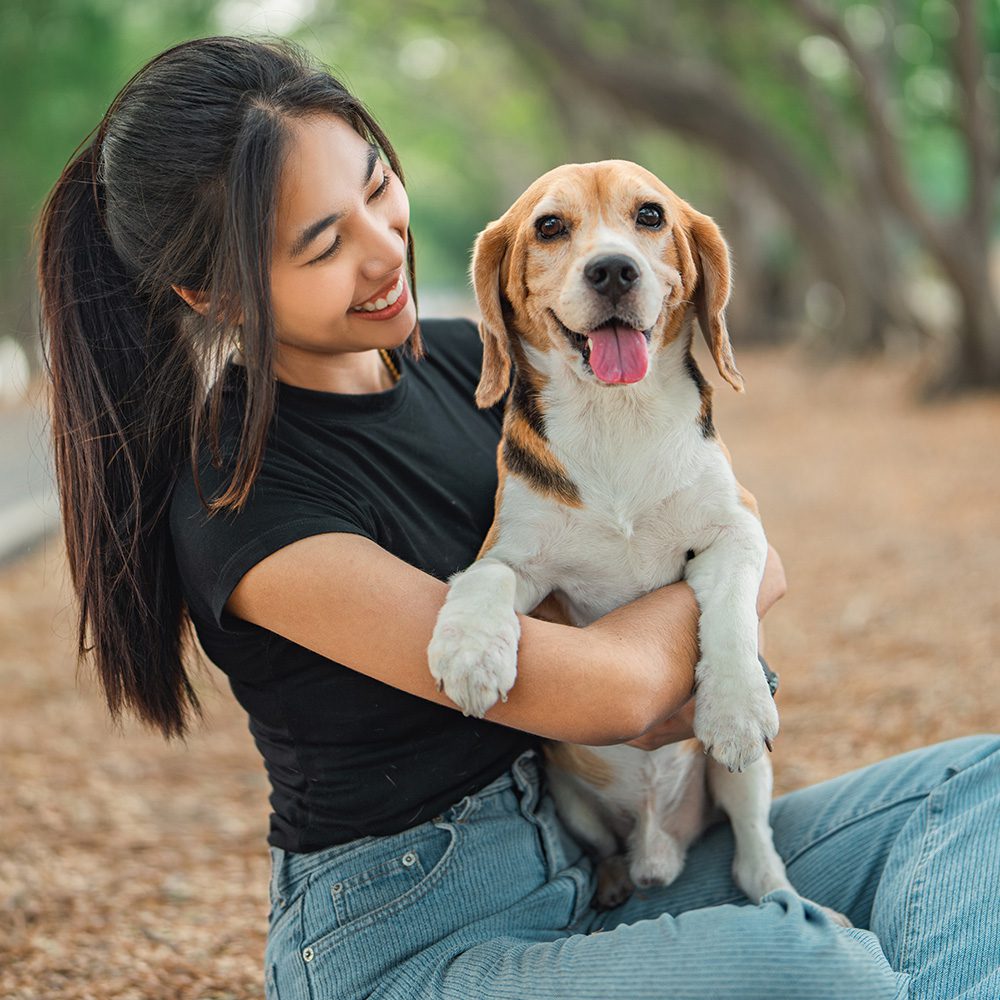 Woman Holding Dog In Lap Outside