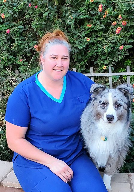 Dr Prato Matthews smiling and sitting outside with her white and grey dog