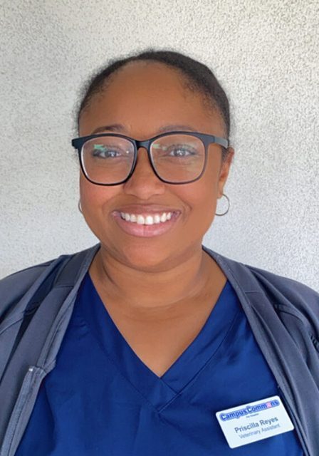 Priscilla wearing blue scrubs and smiling